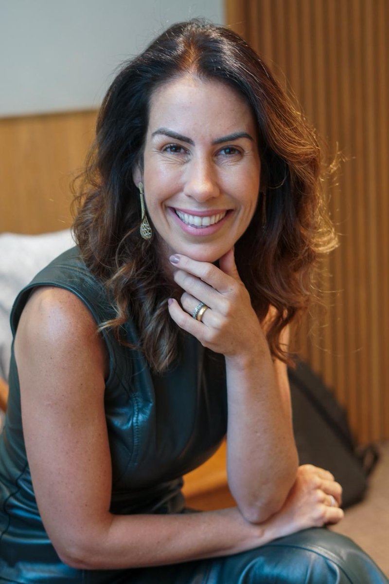 Dra. Renata Moreira Coelho sorrindo, sentada em seu consultório